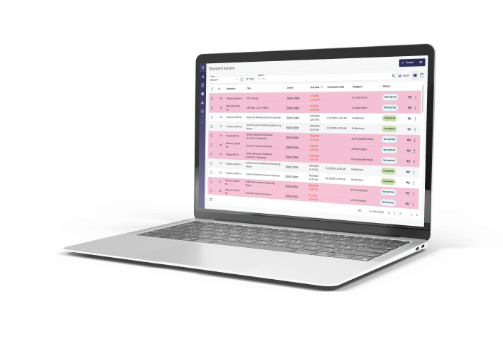 A silver laptop on a white surface shows a project management dashboard with pink-highlighted tasks and columns for status and due dates.